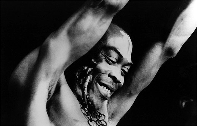 Fela Kuti smiling, with his arms in the air