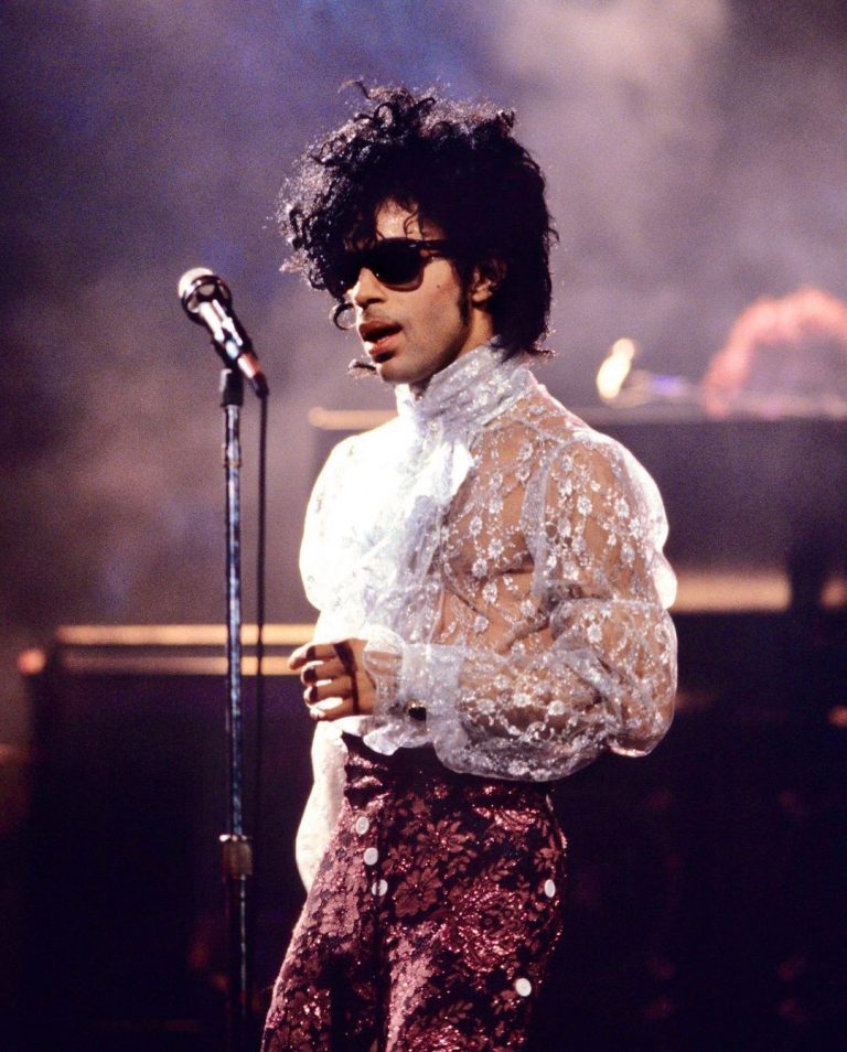 Prince on stage wearing sunglasses and looking cool AF